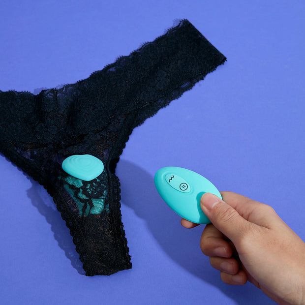 Genvie the willow - green clip on wearable panty vibrator on black lace panty with hand holding bluetooth remote